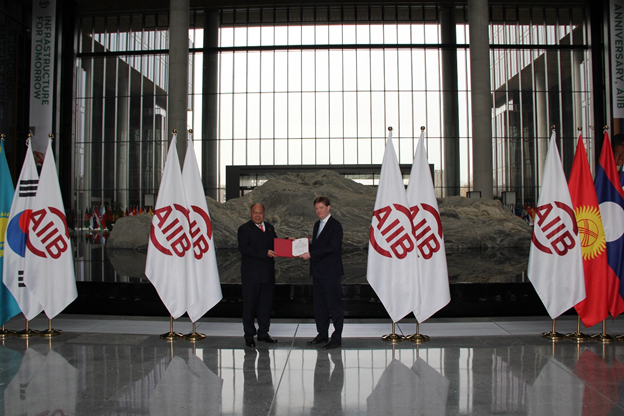 Figure 1: Vice President Sir Danny Alexander presenting the Certificate of Membership of the AIIB to H.E. Ambassador 'Uta'atu.